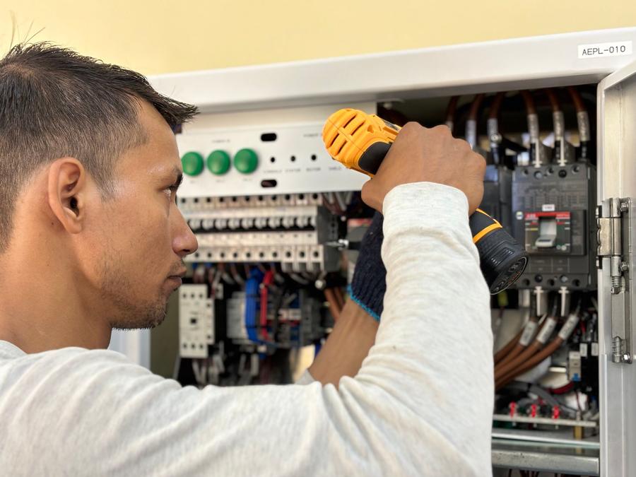 Électricien qui perce un tableau électrique